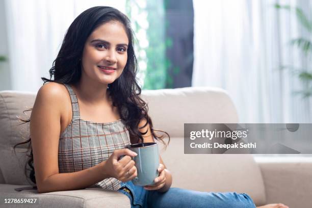 junge frau sitzt auf dem sofa - stockfoto - tee indien trinken stock-fotos und bilder