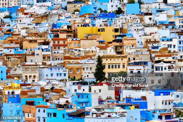 overview of the dense pattern formed by the traditional colorful blue, red, yellow and white-washed houses in the city of chefchaouen - chefchaouen medina stock pictures, royalty-free photos & images