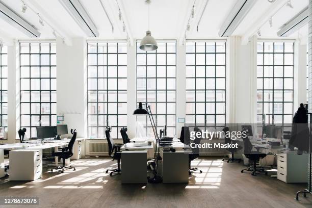 empty table and chair against window at new workplace - werkplek stockfoto's en -beelden