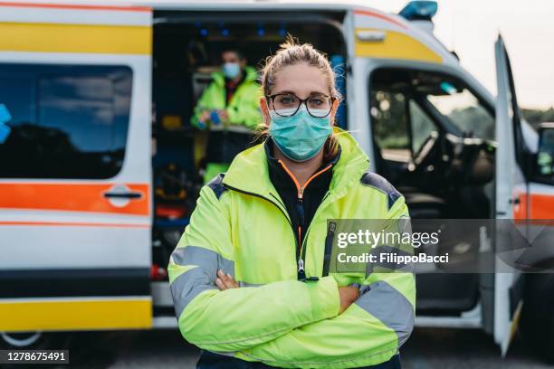 portret van een vrouwelijke paramedicus voor een ziekenwagen openlucht - vitale beroepen stockfoto's en -beelden