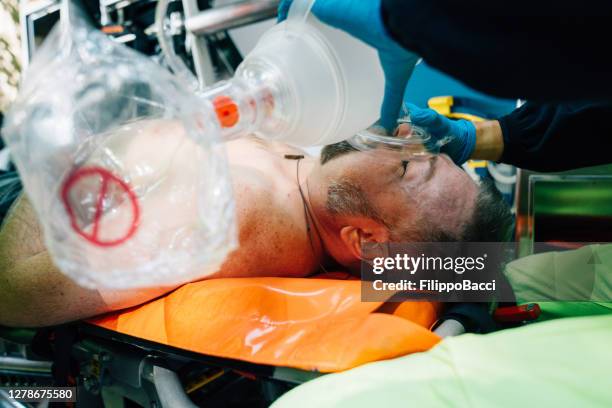 paramedic is helping a man with an ambu bag inside an ambulance - respiratory tract stock pictures, royalty-free photos & images