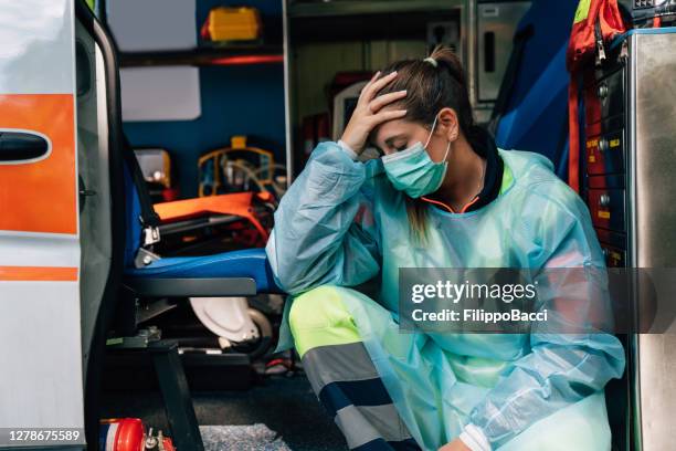 young paramedic woman is sad, sitting on an ambulance - italy coronavirus stock pictures, royalty-free photos & images