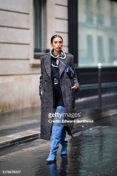 Gabriella Berdugo wears a gray long wool coat, a blue Dior small bag, a black dress with white ruffled collar and floral embroidery, blue pointy high...