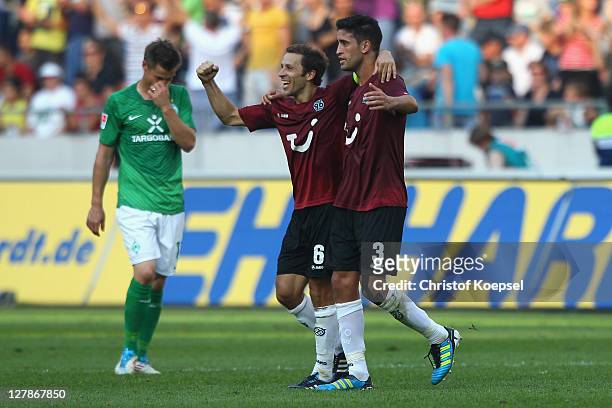 Steven Cherundolo and Karim Haggui of Hannover celebrate the 3-2 victory and Sebastian Proedl of Bremen looks dejected after the Bundesliga match...