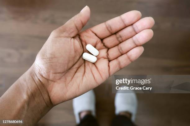 woman holds pills - aspirina foto e immagini stock