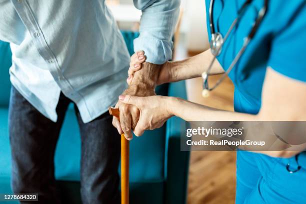 mature female nurse supporting senior man to walk - retirement community staff stock pictures, royalty-free photos & images