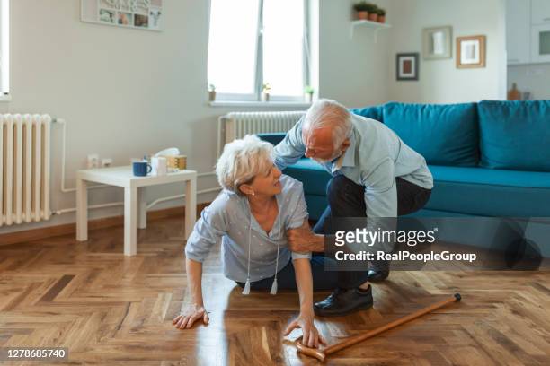 disabled elderly woman had a misfortune and fell on the wooden floor in the living room of her apartment. - falling imagens e fotografias de stock
