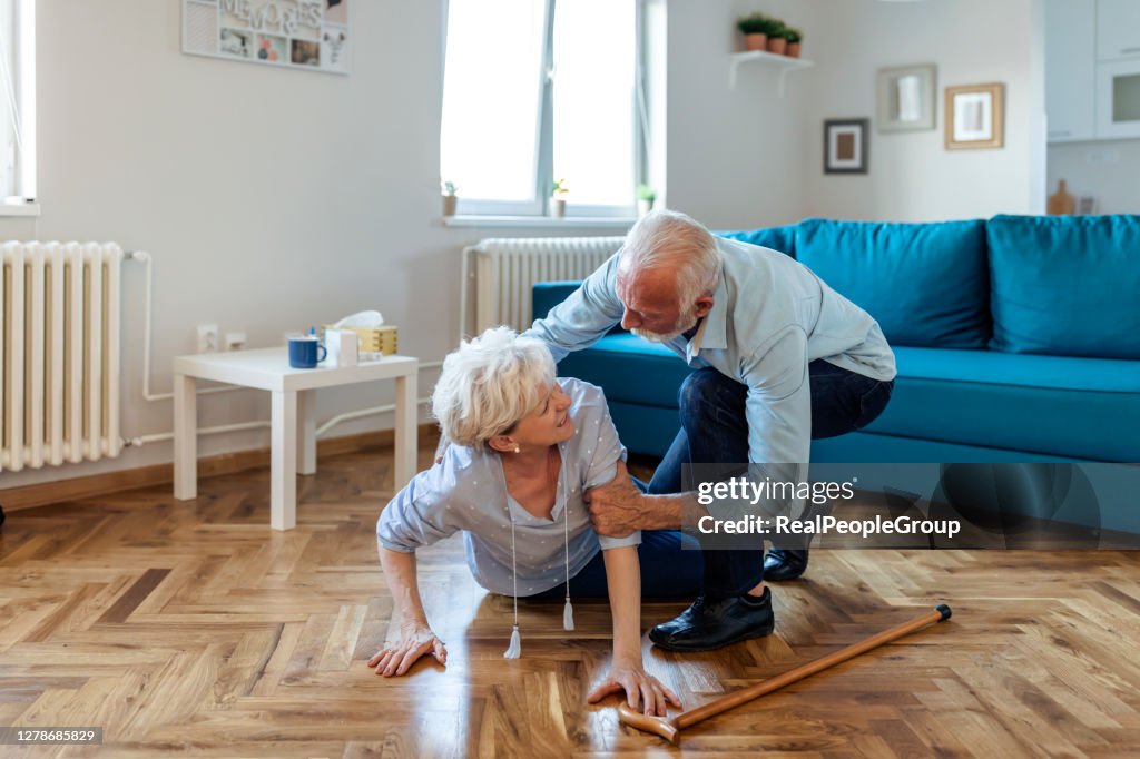 Behinderte ältere Frau hatte ein Unglück und fell auf dem Holzboden im Wohnzimmer ihrer Wohnung.