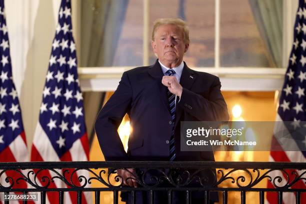 President Donald Trump gestures on the Truman Balcony after returning to the White House from Walter Reed National Military Medical Center on October...