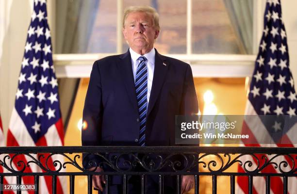President Donald Trump stands on the Truman Balcony after returning to the White House from Walter Reed National Military Medical Center on October...