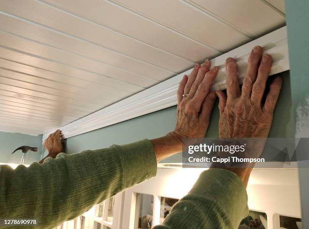 senior couple's hands together installing wood molding inside house - molding a shape stock pictures, royalty-free photos & images