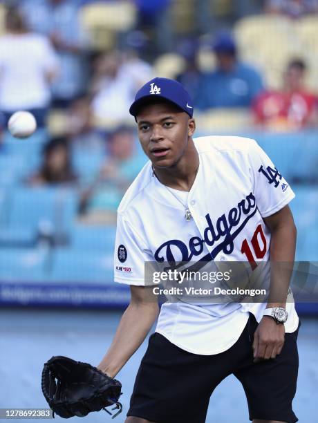 French national soccer player Kylian Mbappe looks to catch a baseball prior to throwing out the ceremonial first pitch prior to the MLB game between...
