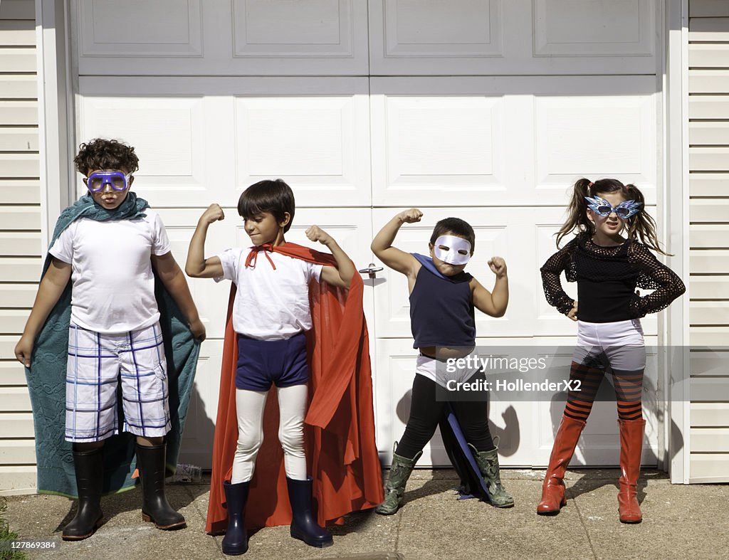 4 kids posing for camera in superhero outfits