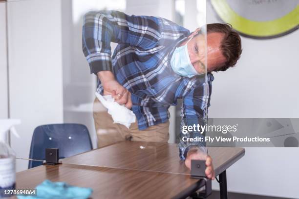 male teacher wearing cloth face mask cleaning classroom - acrylic glass stock pictures, royalty-free photos & images