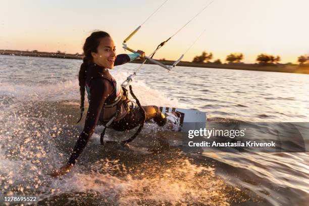 young woman enjoying her kitesurfing success. - surfer wetsuit stock pictures, royalty-free photos & images