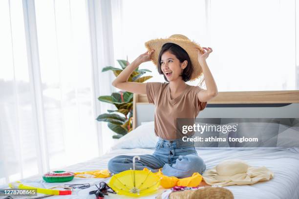 young woman packing backpack in bedroom - backpacker apartment stock-fotos und bilder