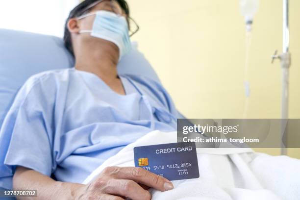 old asian patient man showing credit card with happy and smile on patient bed - accesorio financiero fotografías e imágenes de stock