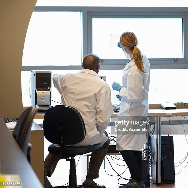 male and female scientists look at a dna gel - look back stockfoto's en -beelden