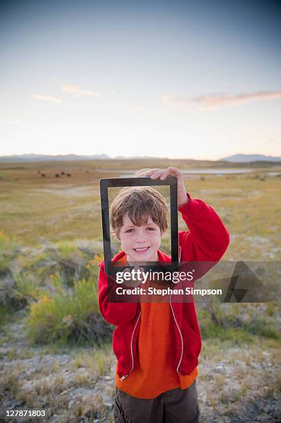 boy showing his portrait on tablet computer - waist up photos stock-fotos und bilder