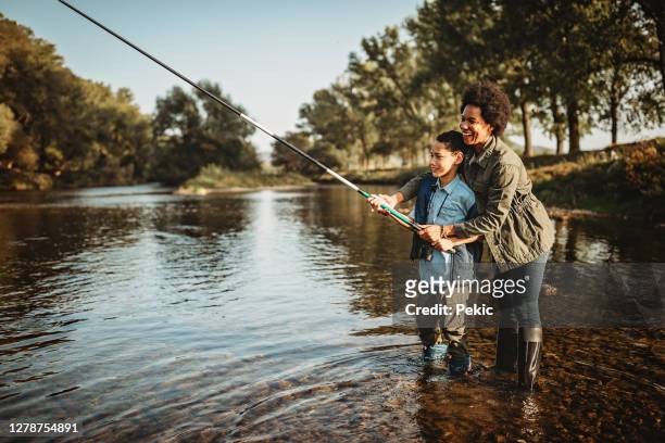 mutter lehrt ihren sohn, wie man einen fisch fängt - fischen stock-fotos und bilder