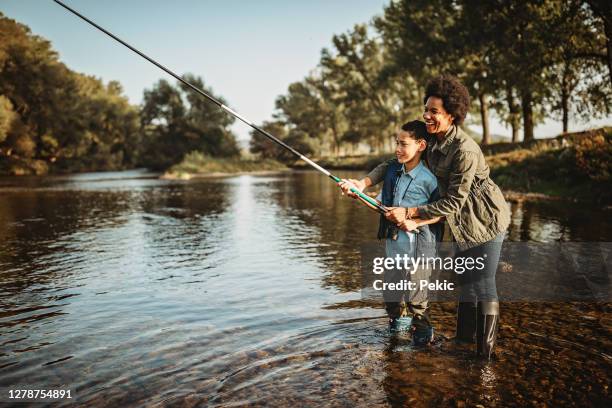 mother teaching her son how to catch a fish - black woman fishing stock pictures, royalty-free photos & images