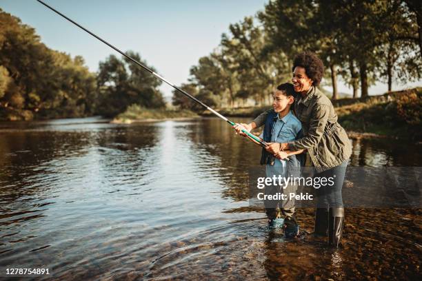 mother teaching her son how to catch a fish - woman fisherman stock pictures, royalty-free photos & images