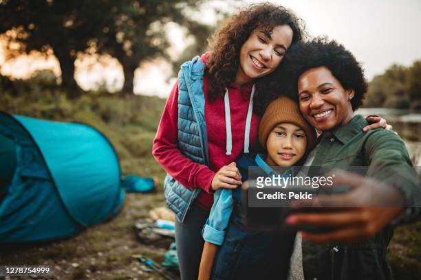 felice famiglia di tre prendendo selfie vicino al loro campeggio - vita attiva foto e immagini stock