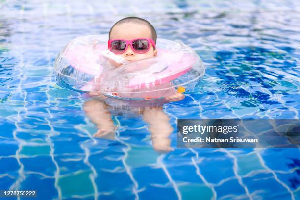 baby swimming with neck swim ring in pool. - ring swimming pool stock pictures, royalty-free photos & images