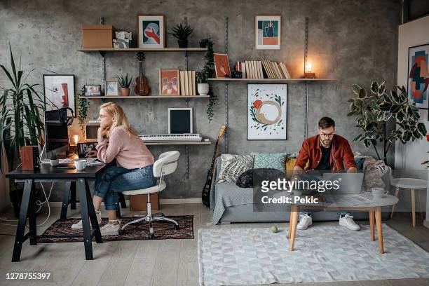 giovane coppia che lavora dal loro ufficio di casa durante la pandemia - lavoro a domicilio foto e immagini stock