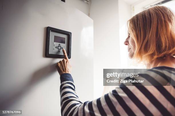 woman changing the settings on the boiler - caldeira imagens e fotografias de stock