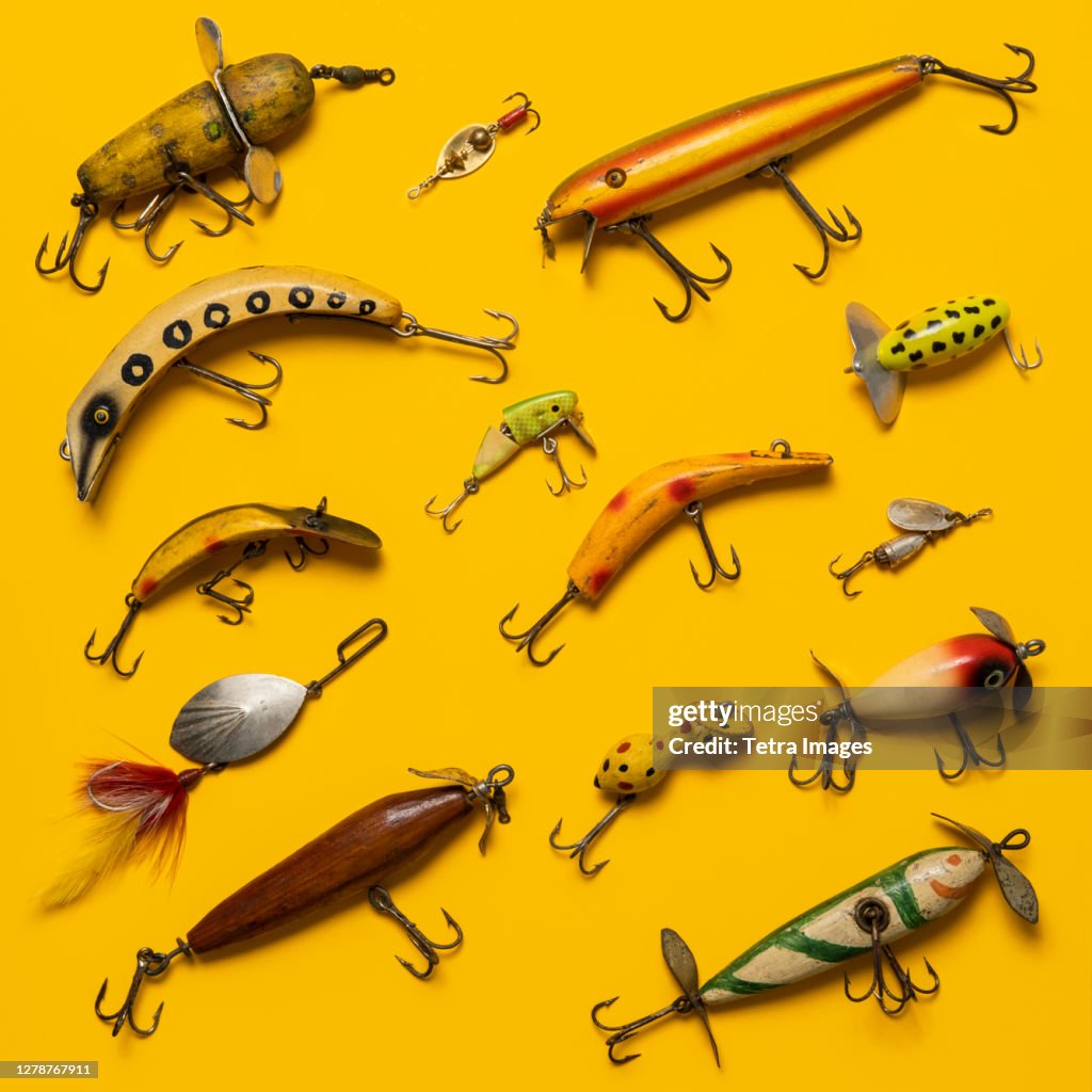 Arranged group of vintage fishing lures on yellow background