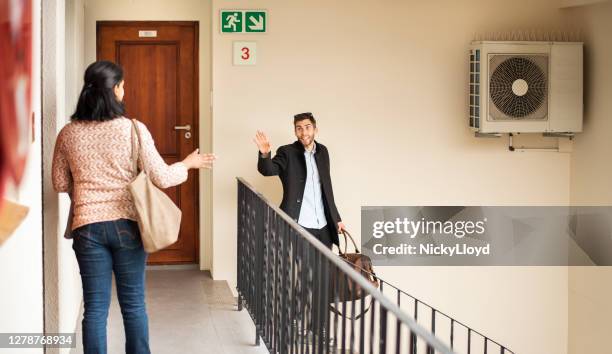 jonge mens die een reiszak draagt die afscheid van zijn buur golft - buurman stockfoto's en -beelden