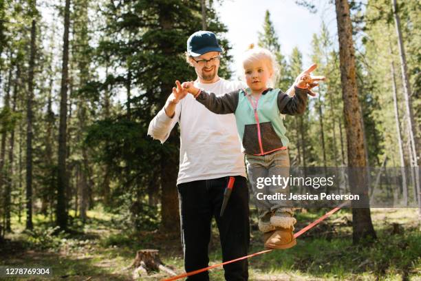 father assisting daughter (2-3) walking on slackline in forest, wasatch-cache national forest - slacklining stock pictures, royalty-free photos & images