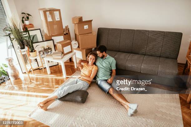 couple moving in new apartment, lying on carpet and sharing love and happiness after moving in. - millennial generation stock pictures, royalty-free photos & images