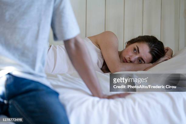 young couple having relationship difficulties in the bedroom - couple on bed stockfoto's en -beelden