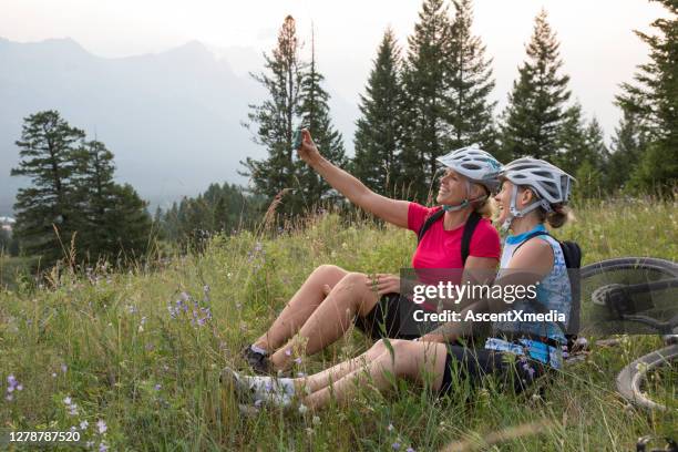 山地自行車手在山間草地上放鬆並拍照。 - 僅成年女人 個照片及圖片檔