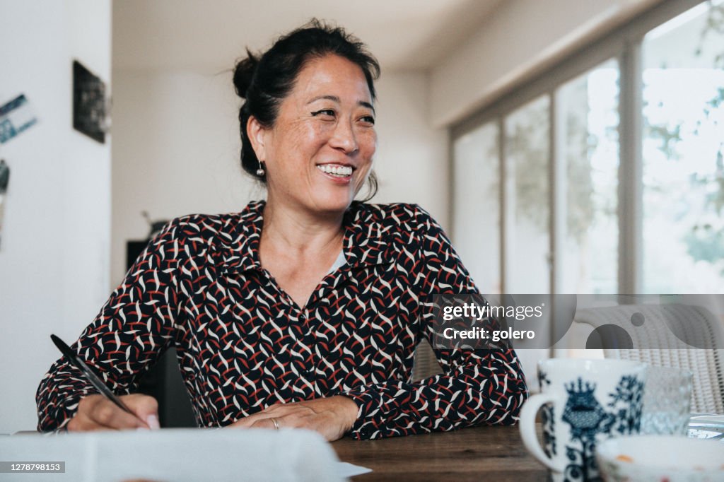 Portrait of smiling elegant woman working writing with pen at wooden table