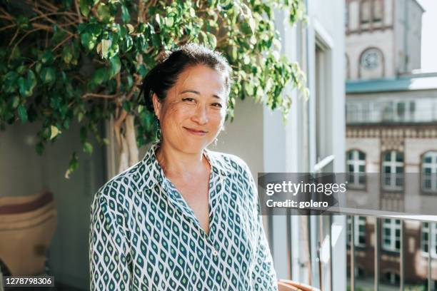 portrait of elegant smiling woman at sunny balcony - 50 54 years outdoors stock pictures, royalty-free photos & images