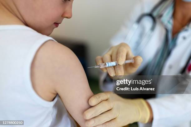 boy getting a flu or coronavirus vaccine in the clinic - arm needle stockfoto's en -beelden