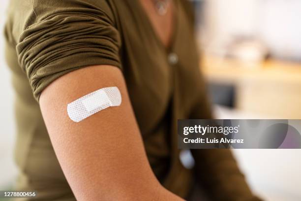 bandage on arm of a female after taking vaccine - venda fotografías e imágenes de stock