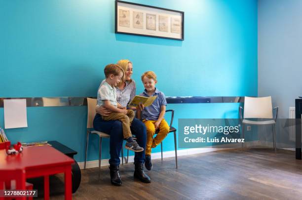 woman with kids sitting at pediatrician waiting room - patients in doctors waiting room stockfoto's en -beelden