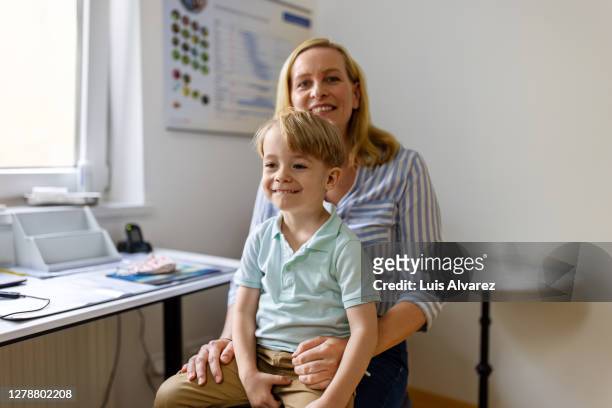 mother and son visiting doctor for routine checkup - doctor children stock-fotos und bilder