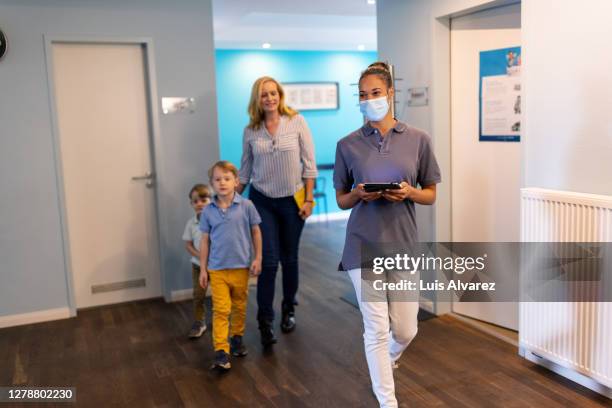 nurse escorting kids and their mother to doctor's office - safe kids day arrivals stock pictures, royalty-free photos & images