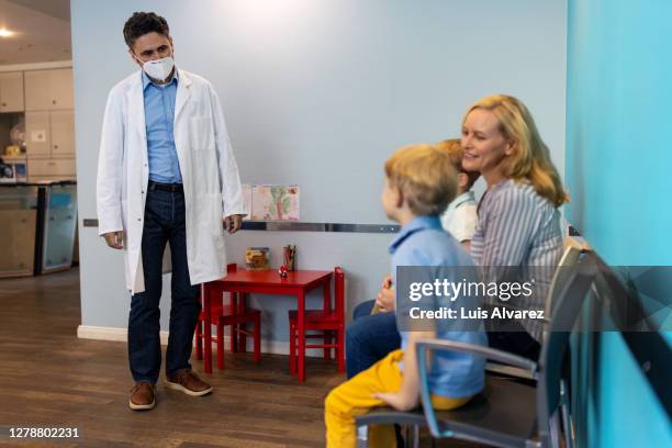 pediatrician wearing mask receiving patient in clinic - arztpraxis empfang stock-fotos und bilder