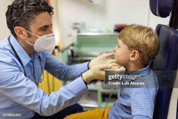 otolaryngologist examining throat of a small boy - throat stock pictures, royalty-free photos & images