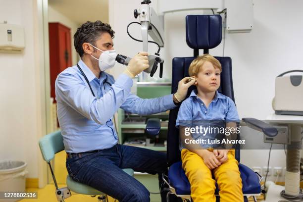ent doctor checking ears of a little boy in his clinic. - infectious disease child stock pictures, royalty-free photos & images