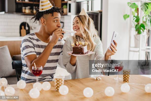 young couple celebrating birthday via video call in home - girlfriend birthday stock pictures, royalty-free photos & images