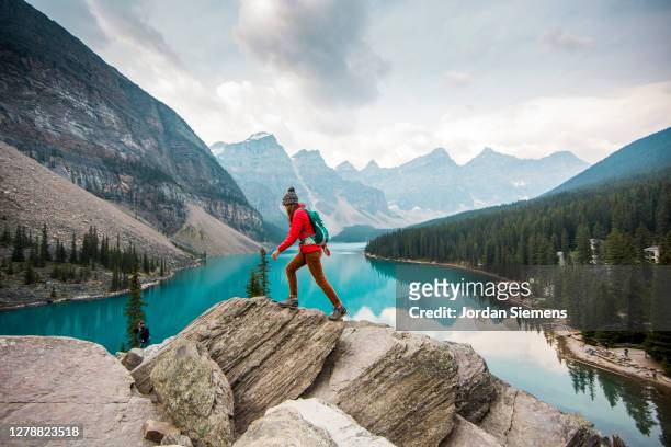 a woman hiking above lake moraine near banff. - abrigo azul fotografías e imágenes de stock
