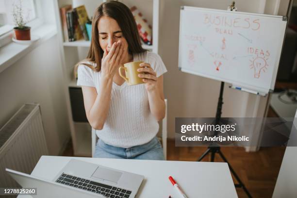 young woman is having coffee to stay concentrated during working from home. - yawning is contagious stock pictures, royalty-free photos & images