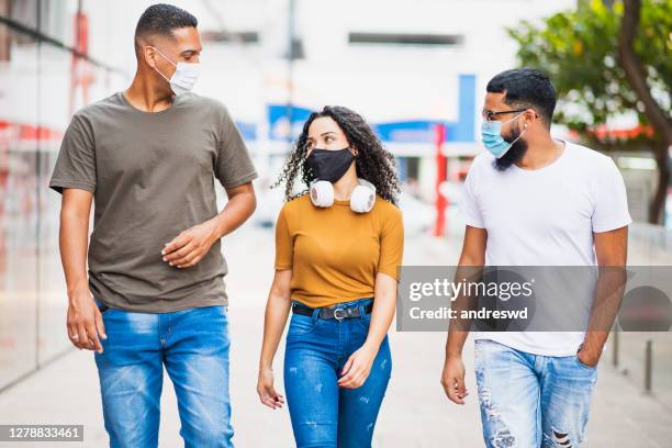 grupo de jovens andando e conversando. usando uma máscara facial contra coronavírus - máscara cirúrgica - fotografias e filmes do acervo